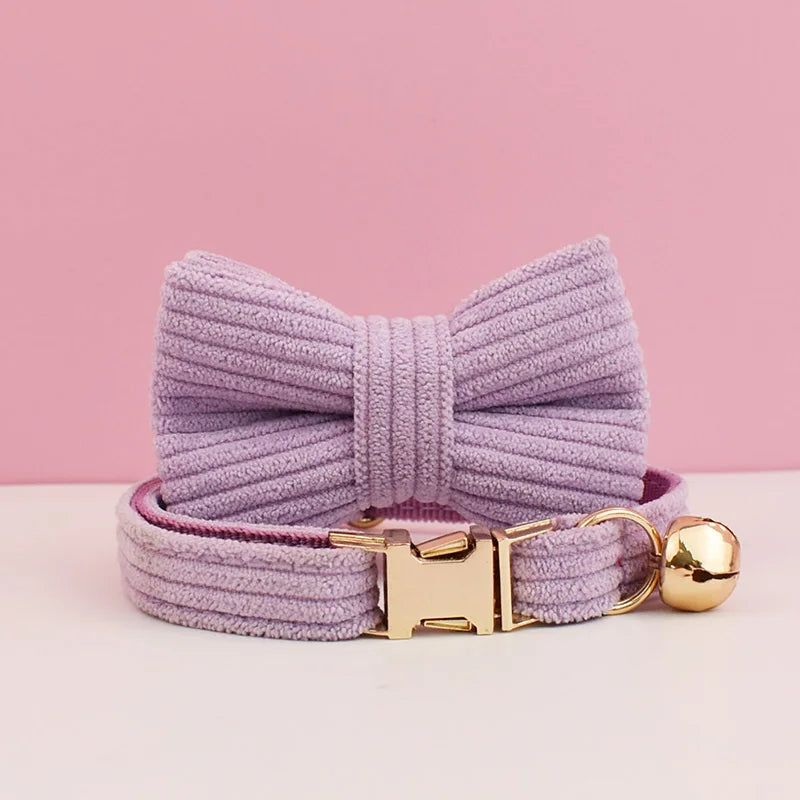 Purple dog collar with a large bow and gold buckle on a pink background