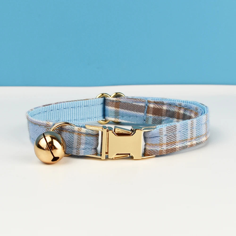Dog collar with gold buckle and bell on a white surface with blue background