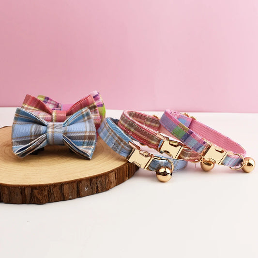 Plaid dog collars with bow ties on a wooden block against a pink background