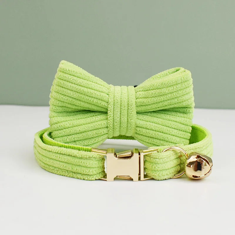Green dog collar with a large bow and gold buckle on a light gray background