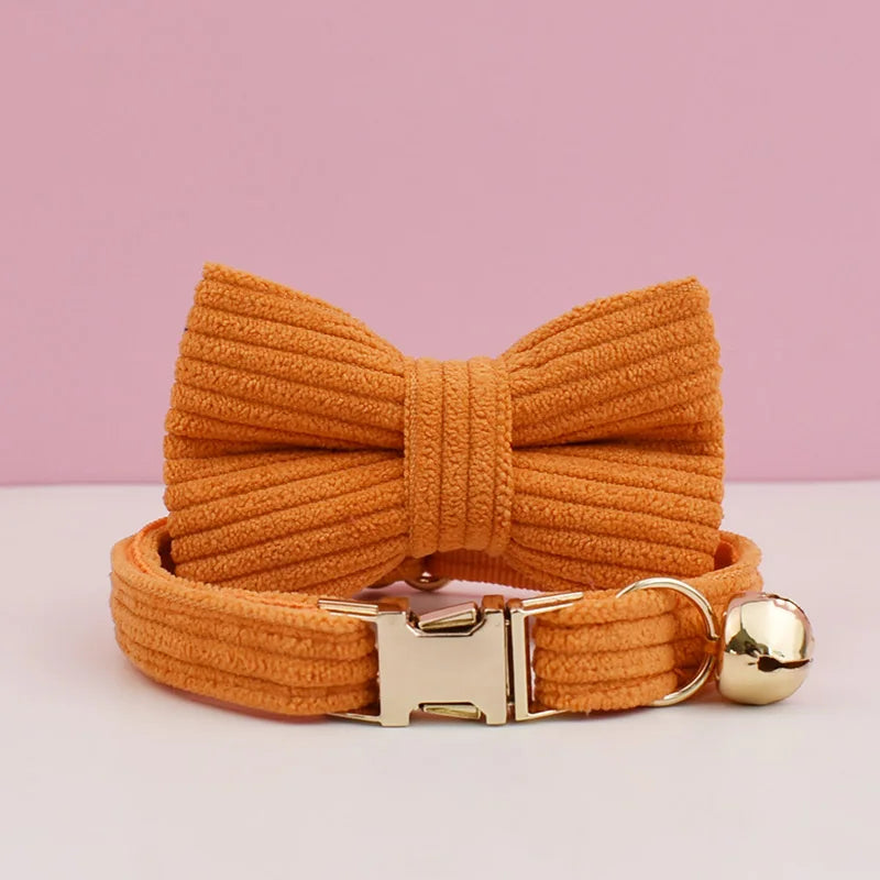 Orange knitted bow tie with a gold buckle and bell on a pink background